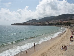 Beach with bathing people, turquoise sea and coastal town in the background, Corsica, Ajaccio,