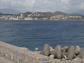 View of a coastal town across the sea, concrete breakwater in the foreground, Corsica, ajaccio,