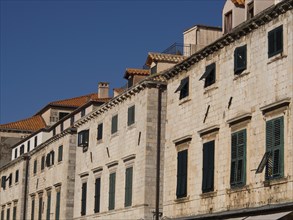 Historic buildings with green shutters and tiled roofs under a blue sky, the old town of Dubrovnik