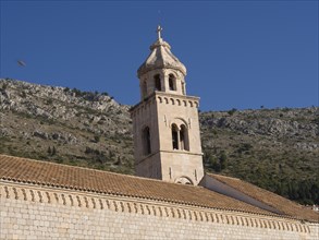 Traditional church tower and buildings against a hilly background, the old town of Dubrovnik with