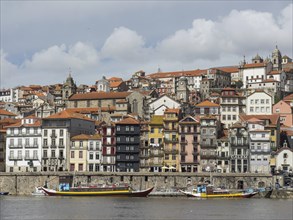 Colourful houses of the old town on the riverside, lively cityscape with boats on the water,