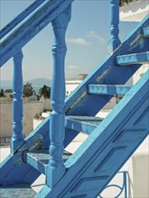 Close-up of a blue staircase with a view of the sea and white buildings, Tunis in Africa with ruins