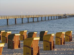 Row of beach chairs on a beach near a pier, peaceful evening, autumn atmosphere on the beach of