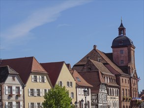 View of an old town with half-timbered houses and a church tower under a clear blue sky, historic
