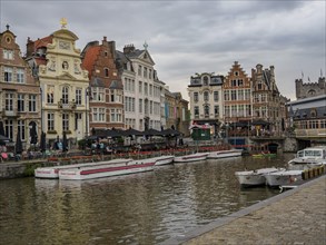 City scene with historic buildings along a canal, boats and a cloudy sky, skyline of a historic