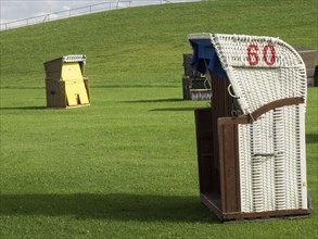 A single beach chair with the number 60 on a green meadow under a cloudy sky, Cuxhaven, Germany,