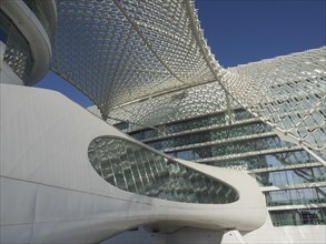 Close-up of a modern building with a striking grid structure and many glass surfaces under a blue