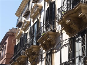 Historic buildings with wrought iron balconies and black shutters in a sunny European city, palermo