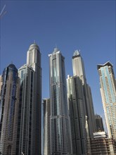 Several tall buildings and skyscrapers rise into a clear blue sky, dubai, arab emirates