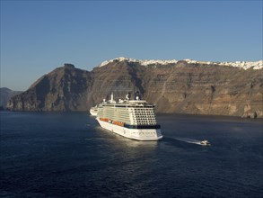 Two cruise ships and a boat in blue water near steep cliffs, brown volcanic island in blue sea with