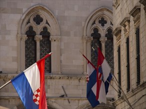 Flags in front of gothic windows of a historic building, the old town of Dubrovnik with historic