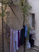 Clothes hanging on a washing line between old buildings, surrounded by rustic ivy, the old town of