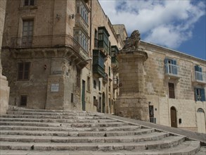 Stone steps lead to historic buildings under a blue sky, Valetta, Malta, Europe