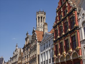 City scene with historic buildings with red facades and a bell tower under a clear blue sky,