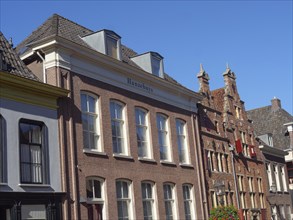 Brick terraced houses with the Hanzehuys in historic architecture under a clear blue sky, red brick