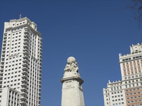 A monument in the middle of two skyscrapers that stand out against the blue sky, Madrid, Spain,