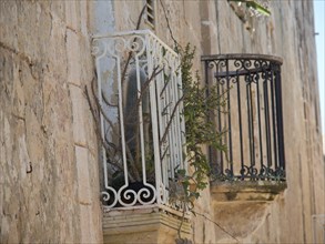 Old iron balconies and plants on a historic stone wall, the town of mdina on the island of malta