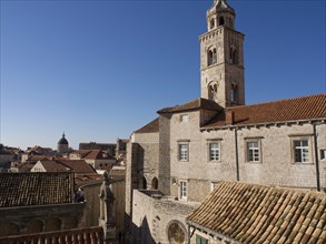 The old town with medieval buildings, a high church tower and red tiled roofs under a clear blue