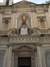 Historic church facade with columns and a golden sculpture, Valetta, Malta, Europe