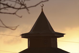 Silhouette of a mosque dome with a crescent at sunset