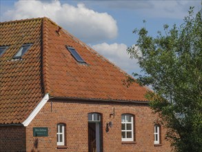 A brick house with a red tiled roof and windows under a blue sky, Baltrum Germany