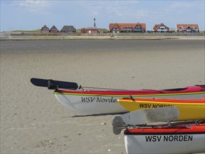Kayaks on the beach with village and blue sky in the background, Baltrum Germany