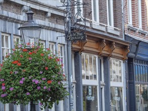 A cobbled street with a vintage-style shop, a street lamp and blooming flowers, Maastricht,
