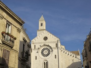 Facade of a historic church with a rose window and a tower against a clear blue sky, The city of
