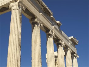 Close-up of ancient temple columns against a clear sky, Ancient buildings with columns and trees on