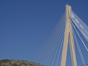 Detailed view of a modern cable bridge in front of a cloudless blue sky, the old town of Dubrovnik