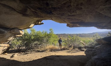 Hikers at the entrance to a cave, Sevilla Art Rock Trail, dry landscape with rock formations,