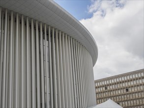 Part of a modern building in Luxembourg with vertical columns and a slightly cloudy sky in the