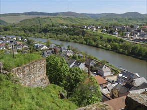 View from above of a town with river, surrounded by green hills and nature, old castle ruins above