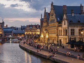 Bruges street scene with busy harbour, historic buildings and people at dusk, historic buildings