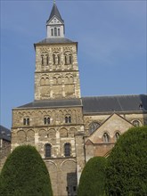 Detailed view of a historic church building with a central tower, surrounded by green bushes and