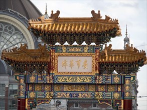 Detailed traditional Chinese Tor tor with golden decorations and bright colours in front of stained