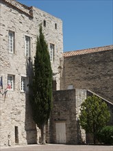 Historic stone building with cypress and flags, under a sunny sky, Provence, le Castellet, France,