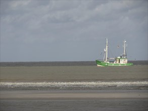A green ship on a calm sea under a partly cloudy sky, Spiekeroog, Germany, Europe