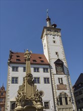 Historic town hall with clock tower, detailed wall painting, artistic fountain in the foreground,