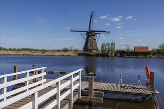 Wooden walkways on a river with an old windmill and clear sky in the background, windmills of