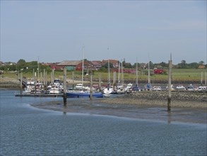 Harbour with many boats moored at jetties, surrounded by a picturesque landscape, Baltrum Germany