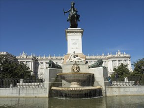 Monument with fountain and equestrian statue on a square, in the background a historic building,