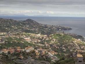 Panorama of a coastal town with a view of the sea and fields under a cloudy sky, Madeira, Portugal,