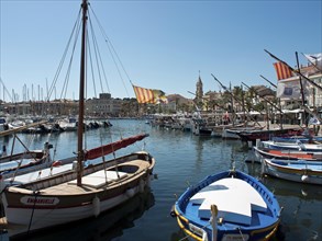 Harbour with many moored boats, buildings and a church in the background under a blue sky, la seyne