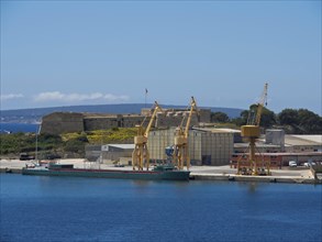 A harbour with cranes and ships, surrounded by buildings and a clear sky, palma de Majorca on the