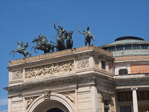 An architectural masterpiece with statues and horses on the roof under a blue sky, palermo in