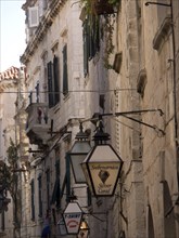 Close-up of a narrow alley in the old town centre with historic buildings, lanterns and various