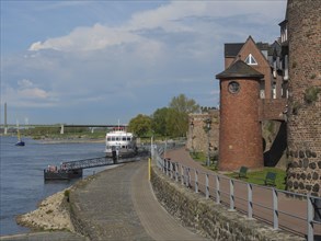Historic harbour with brick walls, boats and a pier on a river, rhine promenade of Rees with