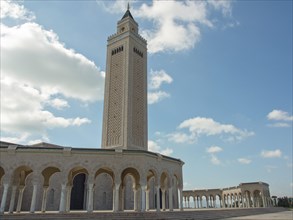Large mosque with high minaret and arches under a cloudy sky, Tunis in Africa with ruins from Roman