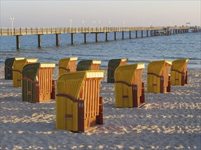Beach chairs near a pier on the beach at sunset, quiet and peaceful atmosphere, autumn atmosphere